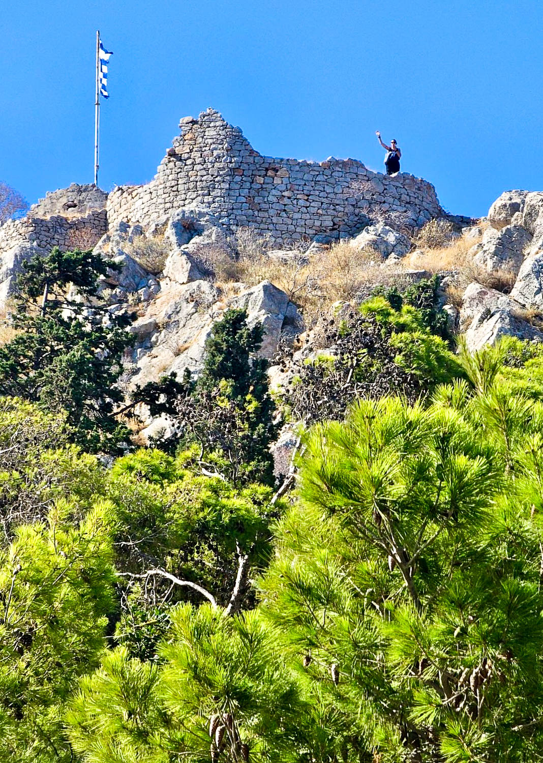 Waving from atop a rocky outcrop near Hydra Town Greece