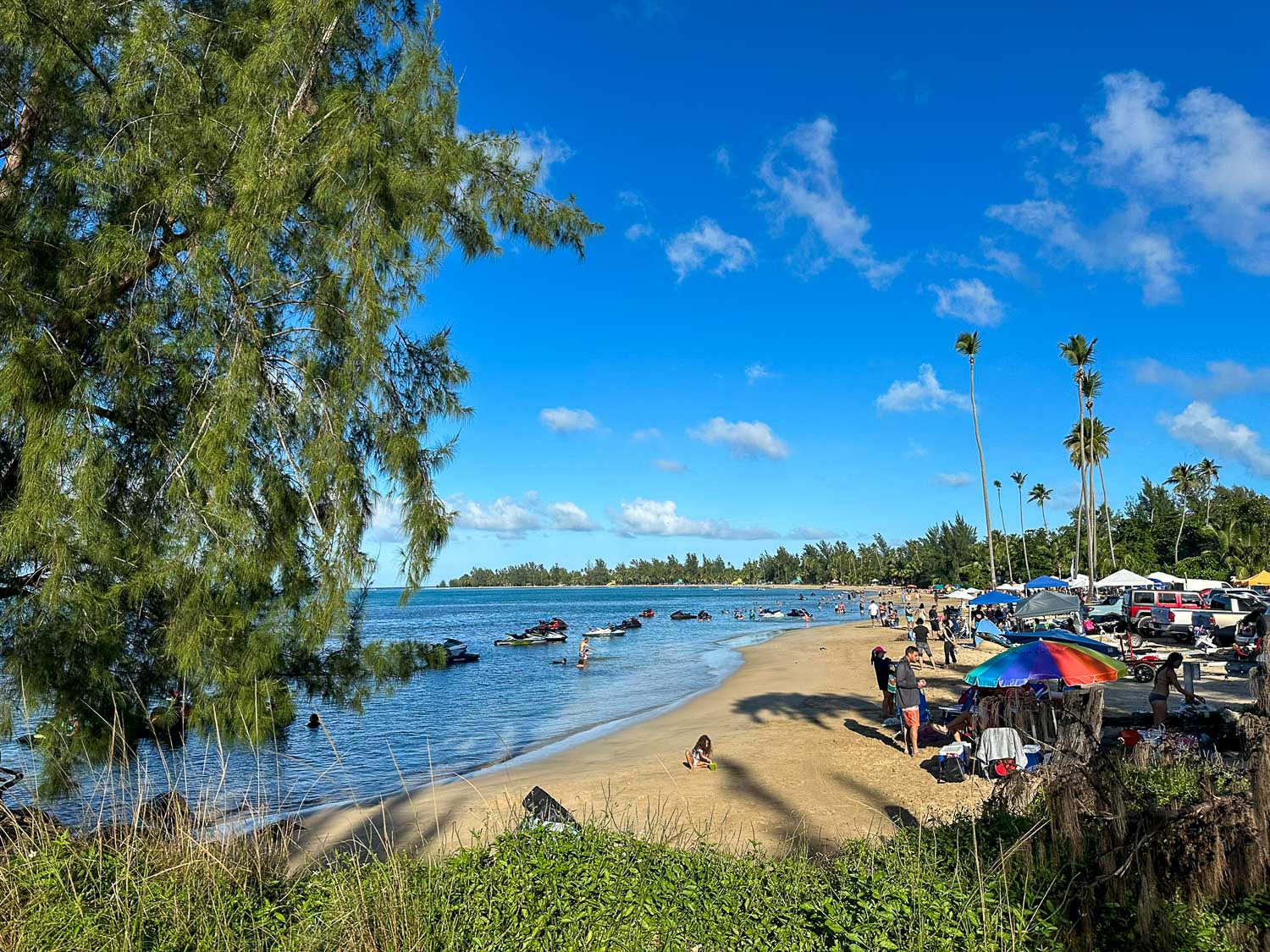 Families relaxing on the sandy shore at Luquillo Beach in Puerto Rico.