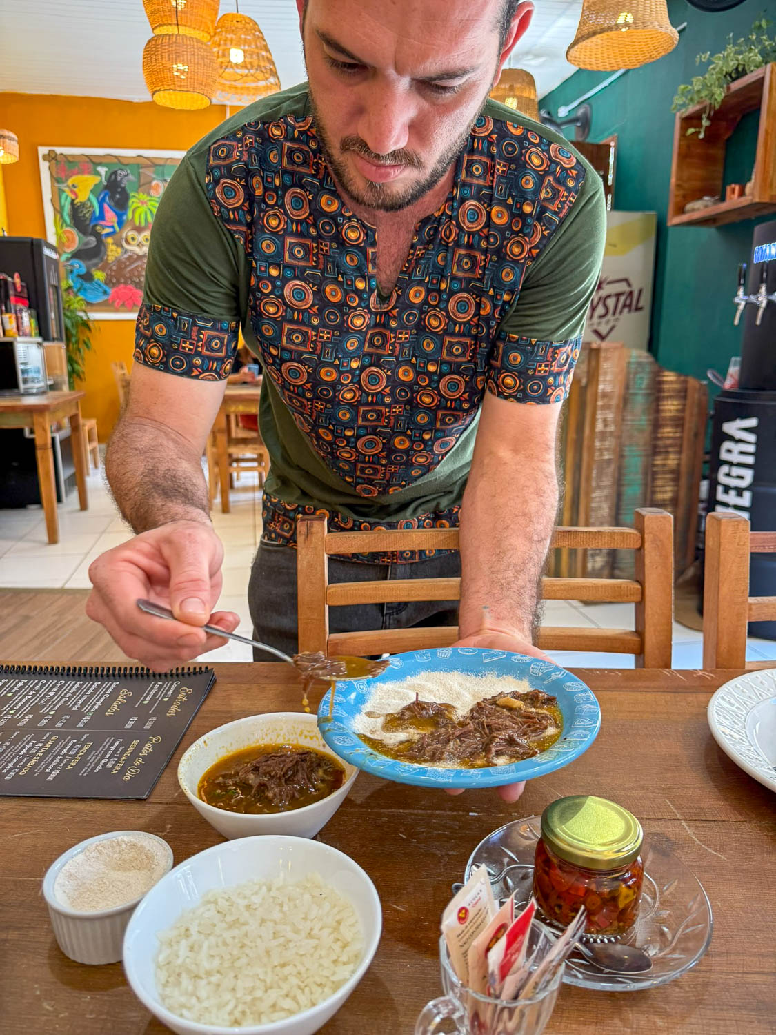 Server presenting a traditional barreado meal at Simples Gastrobar in Morretes, Paraná.