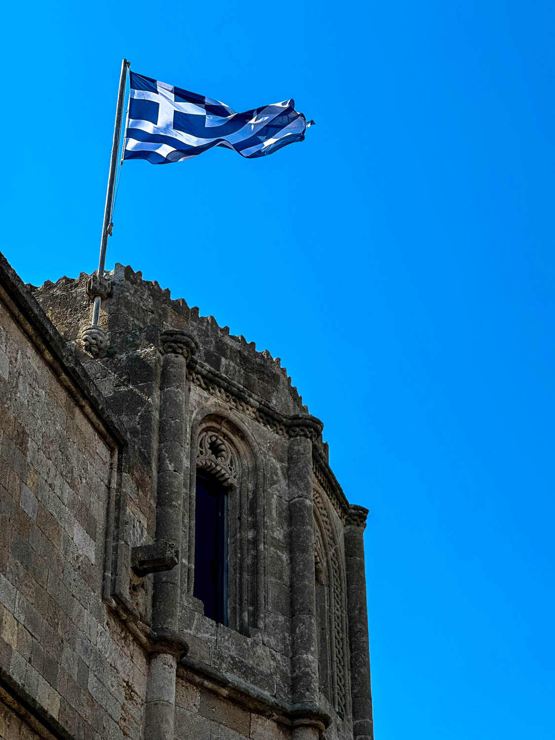 Old Town Rhodes, Greece: The Best Things To Do and See 8 Greek flag flying above the medieval walls of Old Town Rhodes Greece