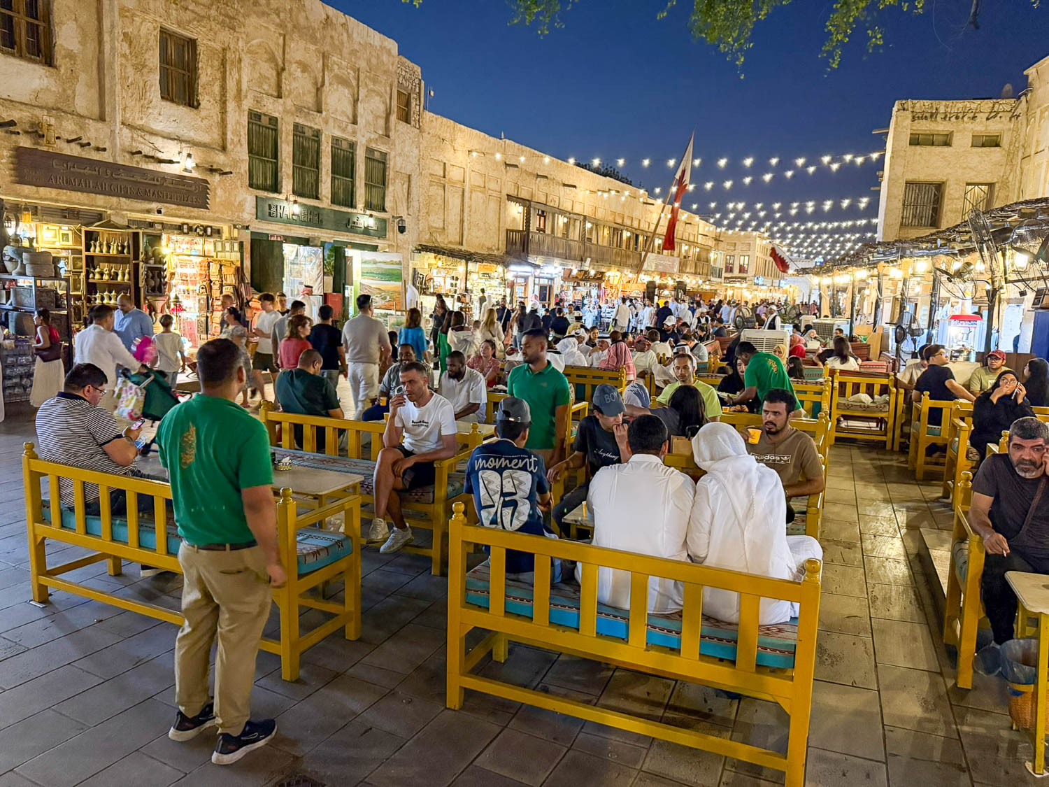 Visitors wearing lightweight modest clothing at Souq Waqif Doha Qatar in warm desert climate