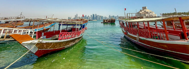 Traditional wooden dhows at Dhow Harbour Doha with the West Bay skyline in the background