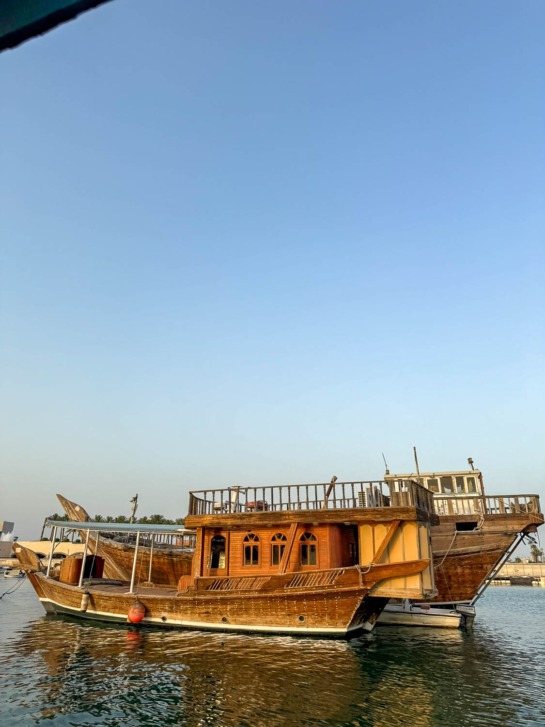 Sunset dhow cruise sailing past ornate traditional boats in Doha Harbour Qatar